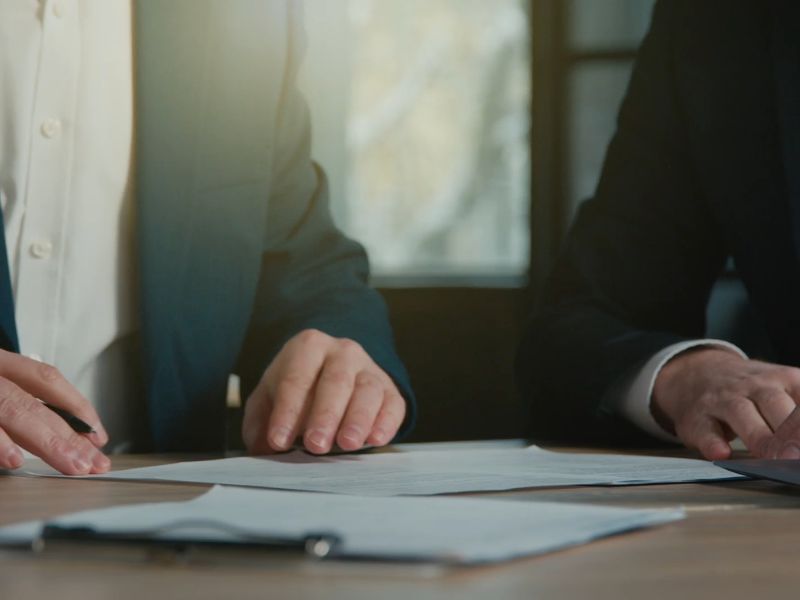 prikaz dva čoveka koji gledaju nešto na papirima i razgovaraju